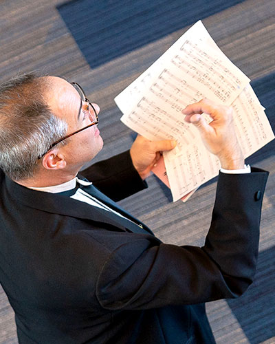 Composer holding note sheets while instructing off-screen musicians