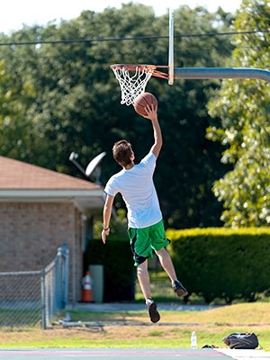 Man jumping to lay up a basketball into a basket on basketball court