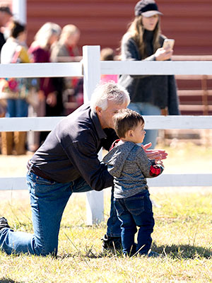 Senior citizen kneeling next to young child talking