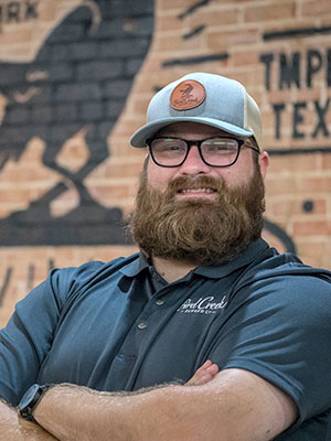 Man with bushy beard with arms crossed smiling