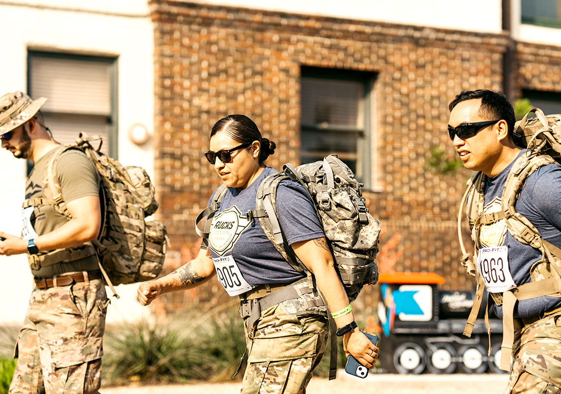 Woman and two men in military uniform with marathon runner tags walking