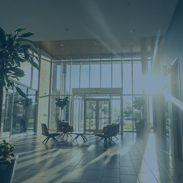 Shot within a building's lobby while sun shines through floor-to-ceiling windows