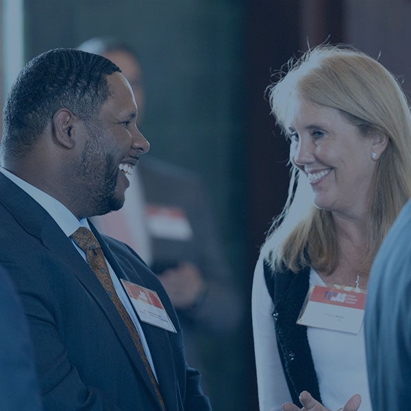 Man in suit talks to woman in business attire during a networking event