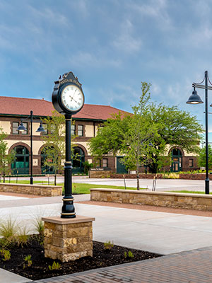 A picture of an standing antique public clock in front of a building