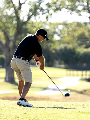 A man hitting a golf ball on a golf course mid-swing