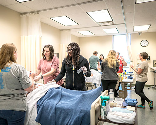 People in a hospital room training on dummies