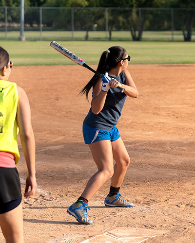 Woman playing baseball and preparing to swing at a pitch while at home plate