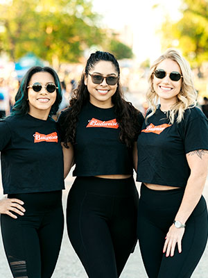 Three women standing side by side with matching uniforms smiling at camera