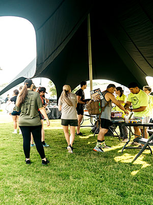 Group of people under a tent receiving information and instructions for an event