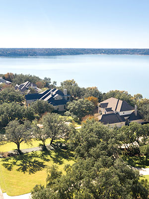 Drone shot of lakeside cabins with green grass and trees