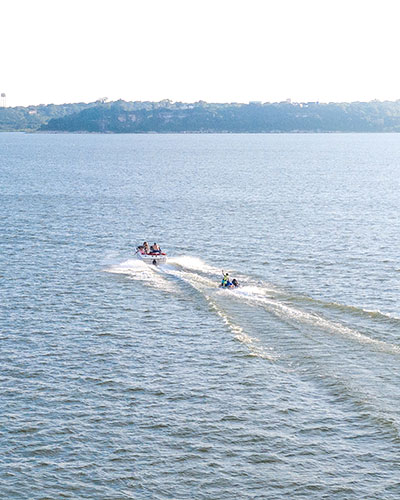 People in a boat dragging a raft on a lake