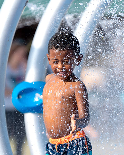 Young boy runs through a water fountain