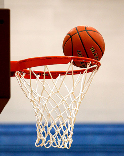 Basketball on the rim of a basketball bucket about to go in