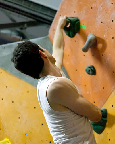 Closeup shot behind a man climbing an indoor rock wall