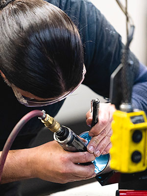 Man hunches over a gizmo utilizing tools to work on the apparatus